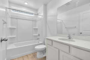 Bathroom featuring toilet, tub / shower combination, wood finished floors, and vanity