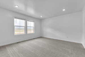Carpeted spare room featuring baseboards, recessed lighting, and visible vents