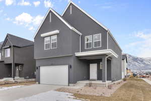 View of front of property featuring an attached garage, stucco siding, a mountain view, covered porch, and driveway
