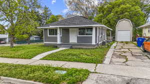 View of front facade featuring an outdoor structure, a garage, concrete driveway, a porch, and central air condition unit