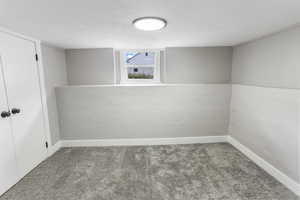 Basement with baseboards, carpet flooring, and a textured ceiling