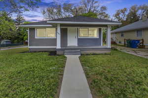 Bungalow featuring covered porch, a lawn, and a shingled roof