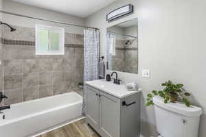 Bathroom with toilet, wood finished floors, shower / bath combo, and vanity