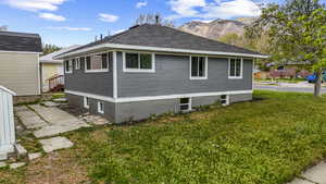 View of side of home featuring a lawn, roof with shingles, and a mountain view