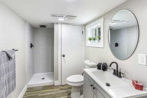 Full bathroom featuring visible vents, a tile shower, wood finished floors, vanity, and toilet