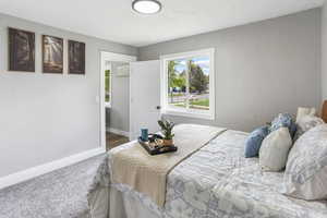 Carpeted bedroom featuring a textured ceiling and baseboards