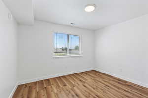 Unfurnished room featuring light wood-style floors, baseboards, and visible vents