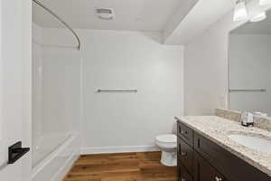 Bathroom with vanity, visible vents, shower / bathtub combination, wood finished floors, and toilet