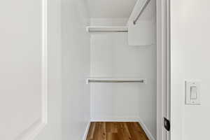 Walk in closet with dark wood-style floors