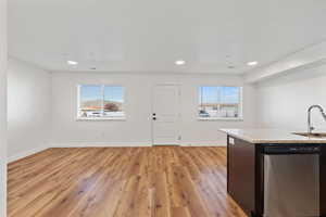 Kitchen with baseboards, light stone counters, a sink, light wood-style flooring, and dishwasher