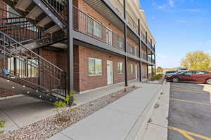 View of building exterior with uncovered parking and stairway