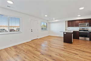 Kitchen featuring visible vents, dark brown cabinets, a sink, baseboards, and stainless steel appliances