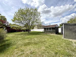 View of yard featuring fence, an outbuilding, and a shed