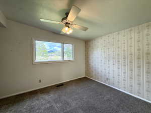 Spare room featuring carpet flooring, ceiling fan, visible vents, and baseboards