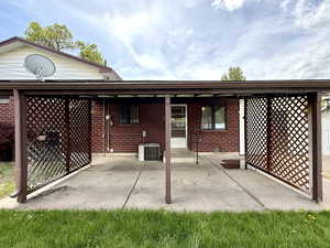 Rear view of house featuring brick siding, a patio area, and central AC