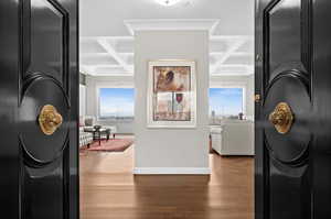 Corridor featuring crown molding, beam ceiling, wood finished floors, baseboards, and coffered ceiling