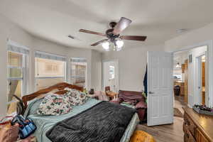 Bedroom featuring visible vents, ceiling fan, and wood finished floors