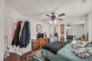 Bedroom featuring visible vents, light wood-style flooring, multiple closets, and a ceiling fan