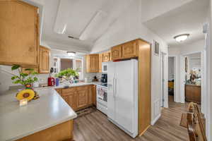 Kitchen featuring light countertops, white appliances, wood finished floors, and visible vents