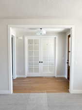 Entrance foyer featuring light wood-style floors, baseboards, french doors, and a textured ceiling