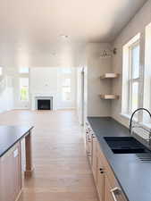 Kitchen with a textured ceiling, visible vents, a fireplace, a sink, and light wood-style floors