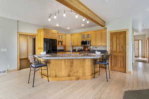 Kitchen featuring a kitchen breakfast bar, stainless steel microwave, visible vents, glass insert cabinets, and black fridge with ice dispenser