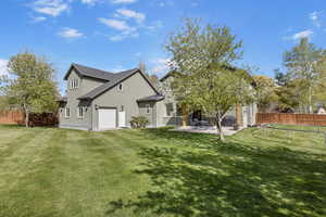 Rear view of property, stucco siding, a yard, mature trees & fence