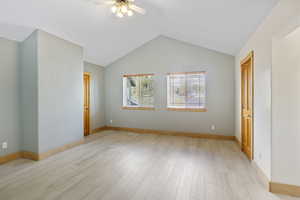 Bedroom 4 featuring a ceiling fan, baseboards, vaulted ceiling, and light wood finished floors, large walk in closets
