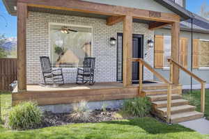 Doorway to property featuring brick siding, a mountain view, and fence, covered patio