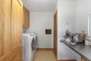 Laundry area with separate washer and dryer, cabinet space, and baseboards