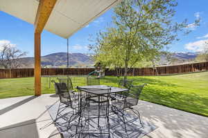 View of patio / terrace with a playground, a mountain view, a fenced backyard, and outdoor dining space