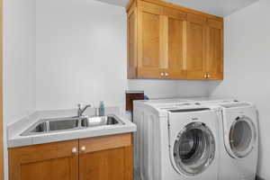 Washroom with a sink, washer and clothes dryer, and cabinet space