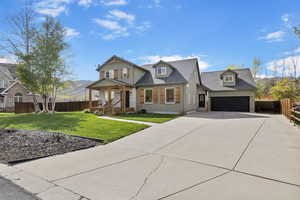 View of front of property featuring covered porch, a front yard, fence, concrete driveway, and an attached garage