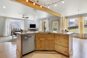 Kitchen with stainless steel dishwasher, open floor plan, a wealth of natural light, and light wood-style floors