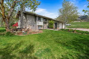 Rear view of house featuring a lawn, a garage, and a chimney