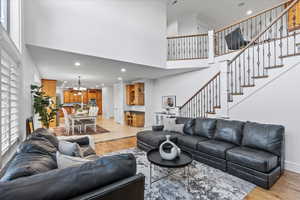 Living room featuring recessed lighting, a towering ceiling, a notable chandelier, and stairway