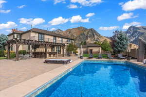 View of pool with outdoor dry bar, a patio, a fenced in pool, a mountain view, and a pergola