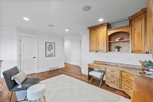 Office space with dark wood-style flooring, visible vents, baseboards, ornamental molding, and recessed lighting