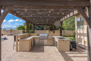 View of patio / terrace featuring a sink, an outdoor kitchen, a fenced backyard, and a grill