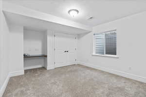 Interior space with carpet floors, baseboards, a textured ceiling, and visible vents