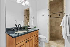 Bathroom with vanity, tile patterned flooring, toilet, and tiled shower