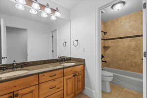 Full bathroom with tile patterned flooring, a sink, toilet, and shower / washtub combination