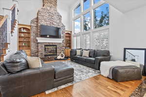 Living room with a fireplace, built in shelves, wood finished floors, a high ceiling, and stairs