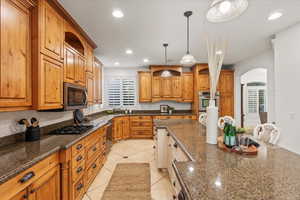 Kitchen with arched walkways, appliances with stainless steel finishes, a healthy amount of sunlight, and recessed lighting