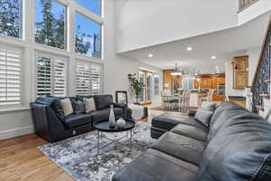 Living area featuring a towering ceiling, baseboards, stairway, recessed lighting, and light wood finished floors