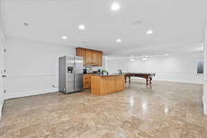 Kitchen featuring visible vents, a kitchen island, dark countertops, stainless steel fridge, and recessed lighting