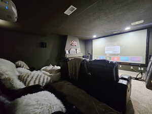 Home theater featuring visible vents, baseboards, recessed lighting, a textured ceiling, and carpet flooring