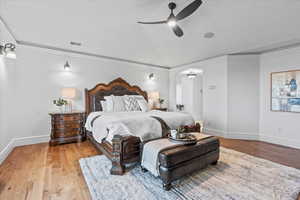 Bedroom featuring light wood-style floors, arched walkways, baseboards, lofted ceiling, and visible vents