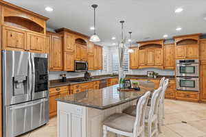 Kitchen with a kitchen island, stainless steel appliances, open shelves, and light tile patterned floors