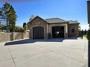 View of front of house with a garage, fence, driveway, and stone siding